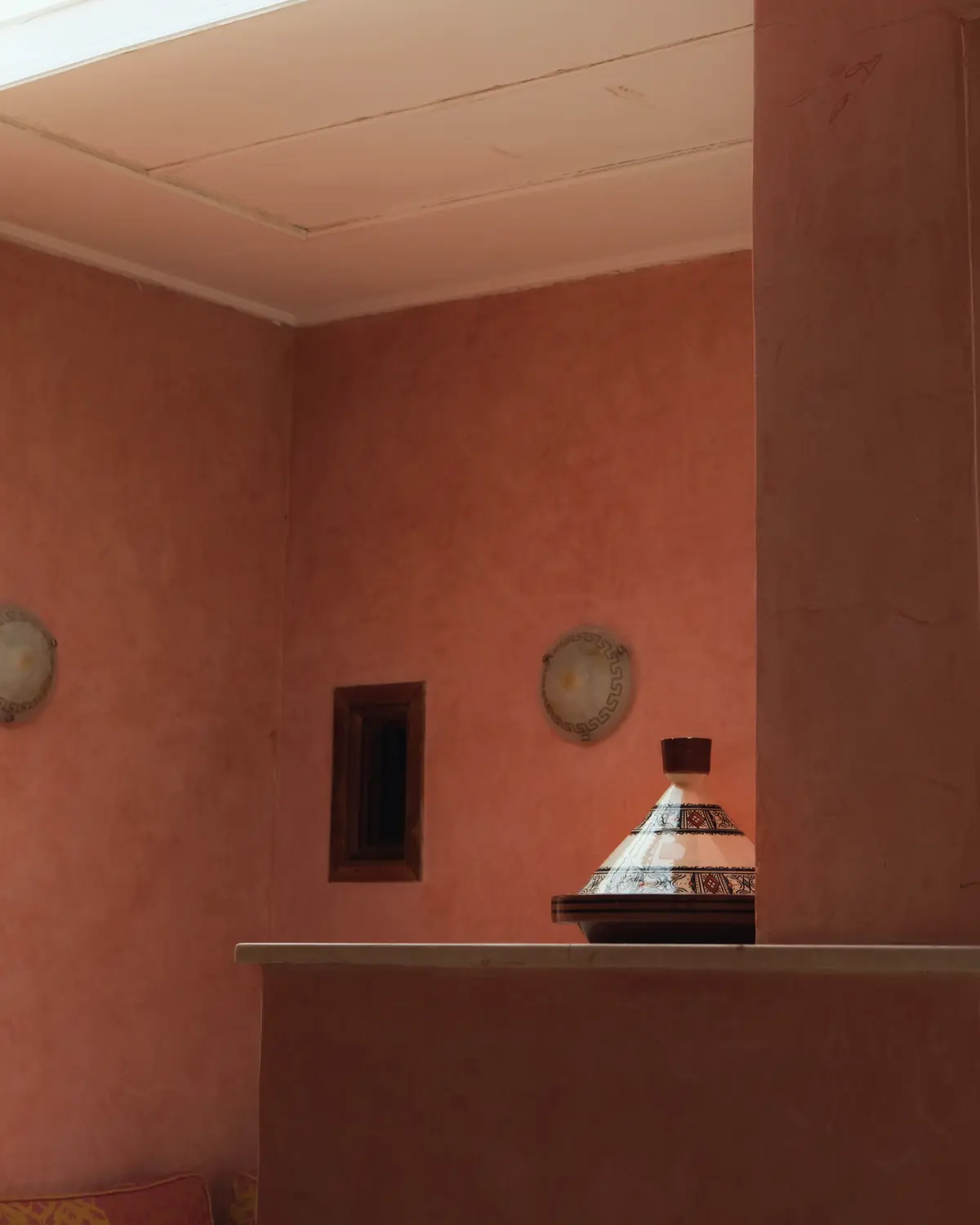 Ochre-walled interior bathed in light, a tagine dish resting on a console