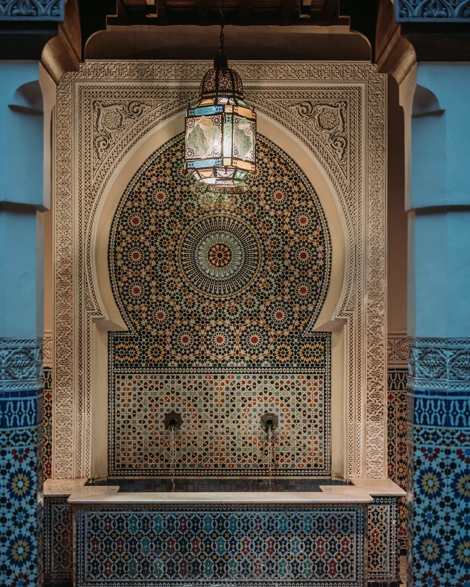 Zellige wall fountain beneath a carved arch